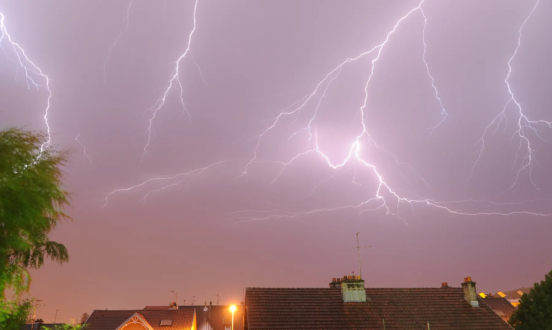 A summer thunderstorm lighting up the sky over a row of rooftops
